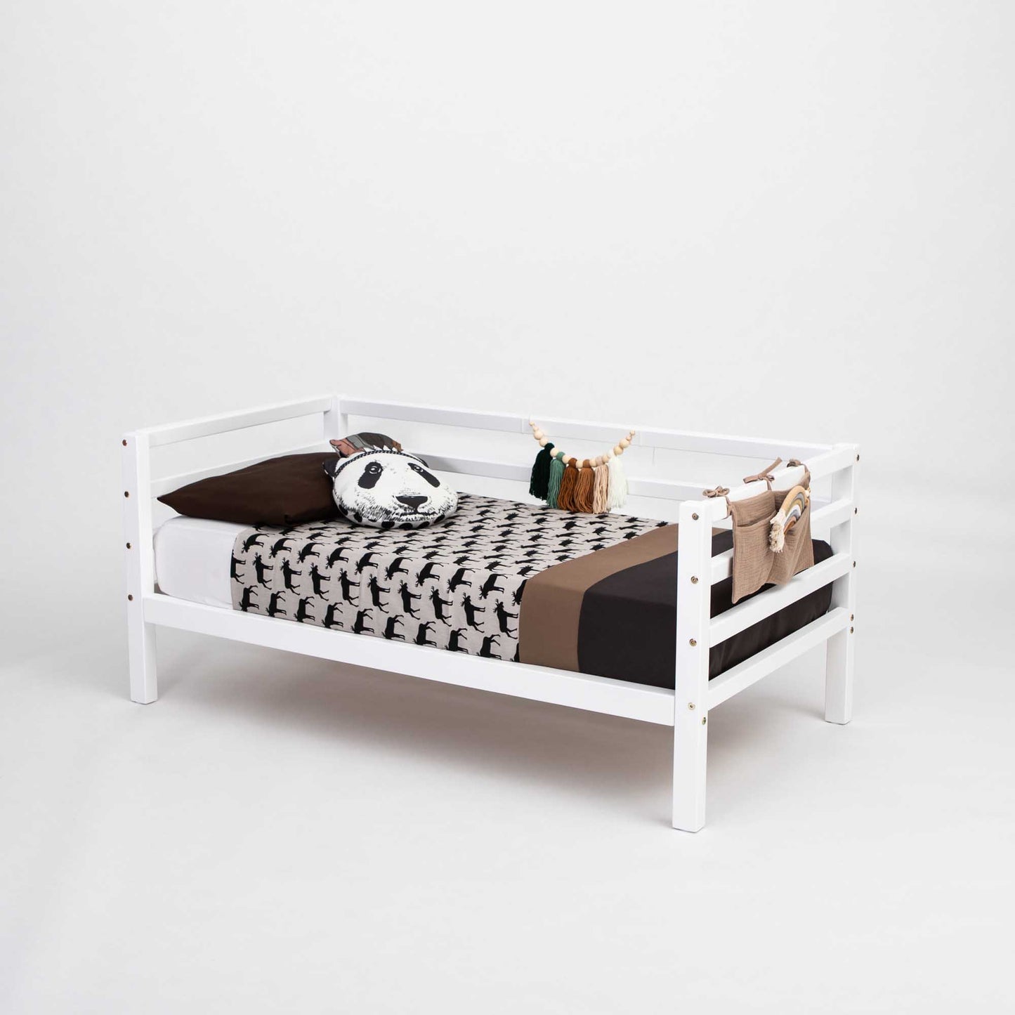 The Kids' bed on legs with a 3-side horizontal rail is made of solid wood and shown with a black and white animal print blanket, brown bedding, and a panda pillow, all against a plain white background.