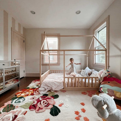 A cozy sleep haven for a child, featuring a Sweet Home From Wood Montessori floor house bed with rails and a plush rug.
