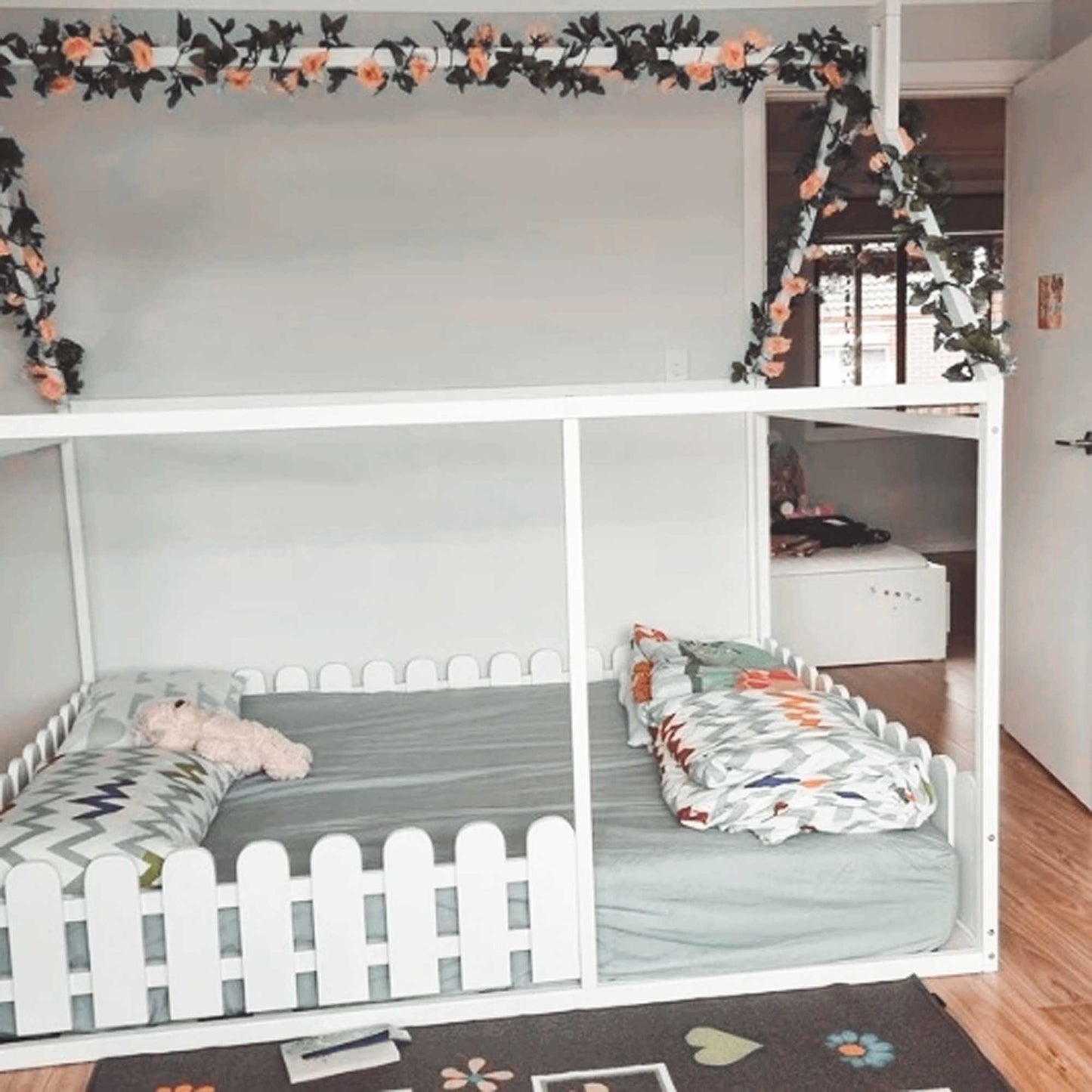 A child's bedroom with a platform house bed with a picket fence.
