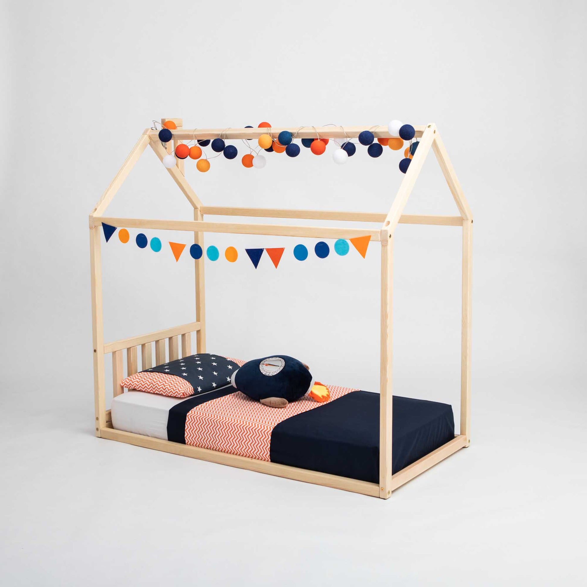 A cozy House-frame bed with a headboard from Sweet Home From Wood, made of wood and adorned with pom poms.
