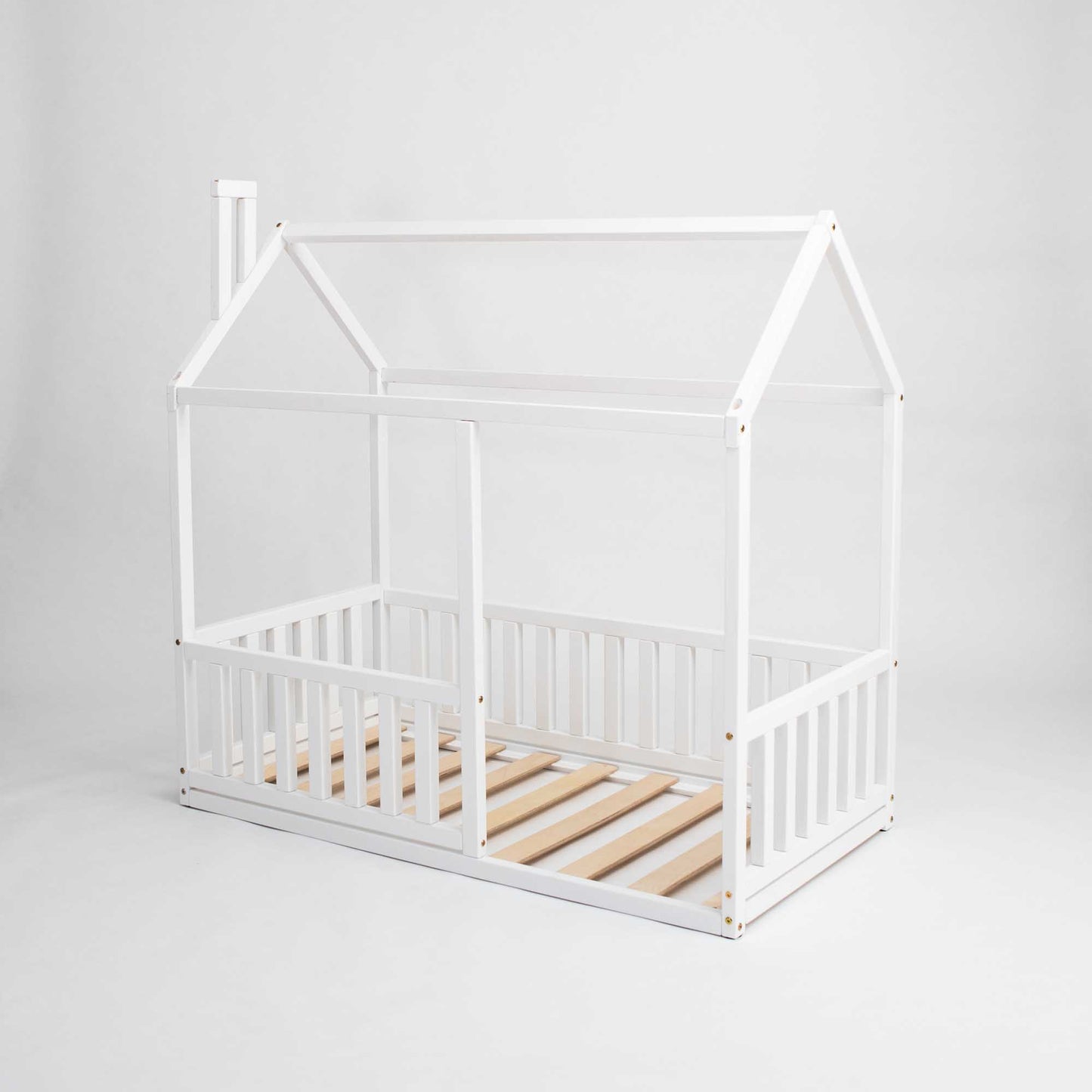 Experience the ultimate cozy sleep haven with our Sweet Home From Wood Montessori floor house bed with rails, featuring a vertical rail fence and crafted from white wooden slats.