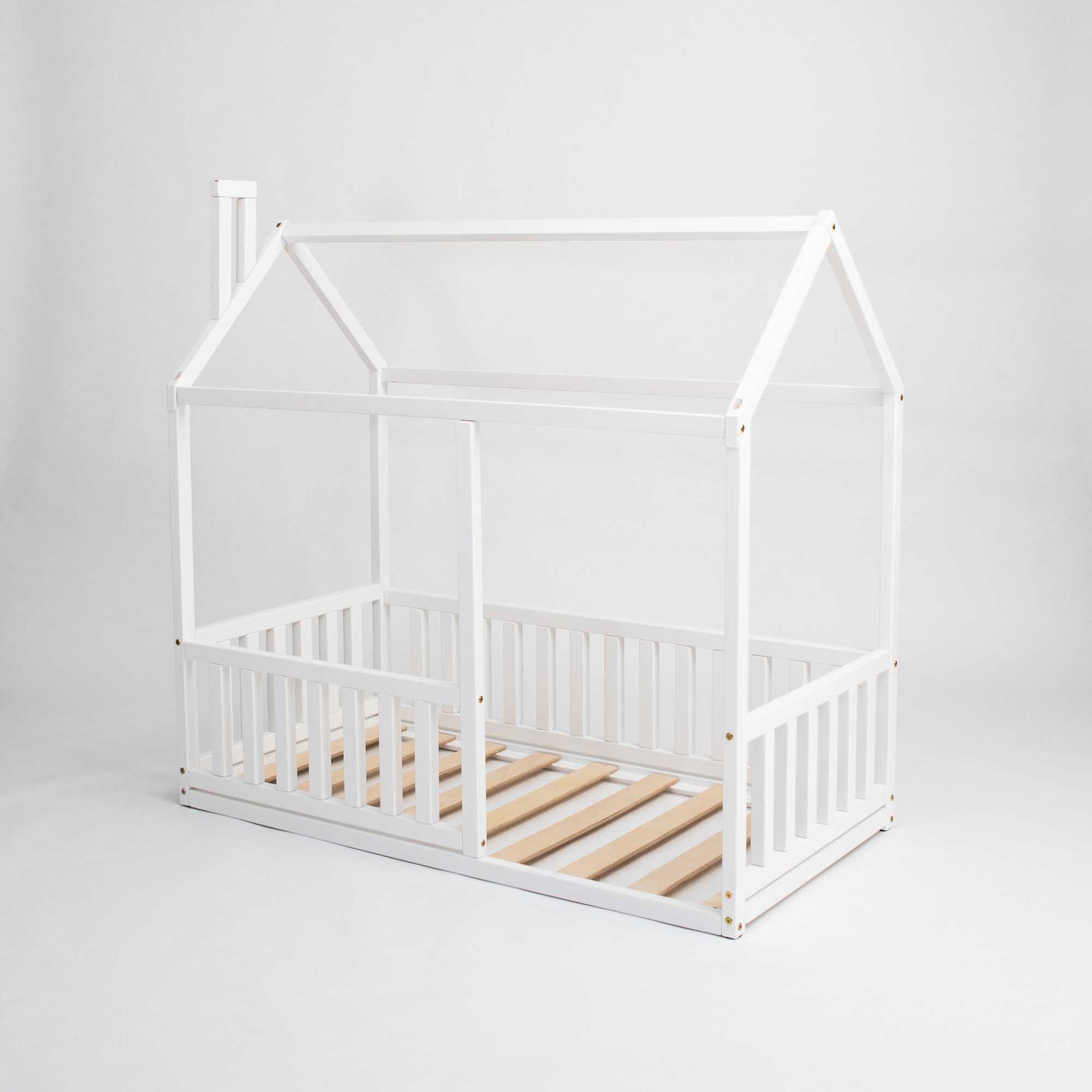 Experience the ultimate cozy sleep haven with our Sweet Home From Wood Montessori floor house bed with rails, featuring a vertical rail fence and crafted from white wooden slats.