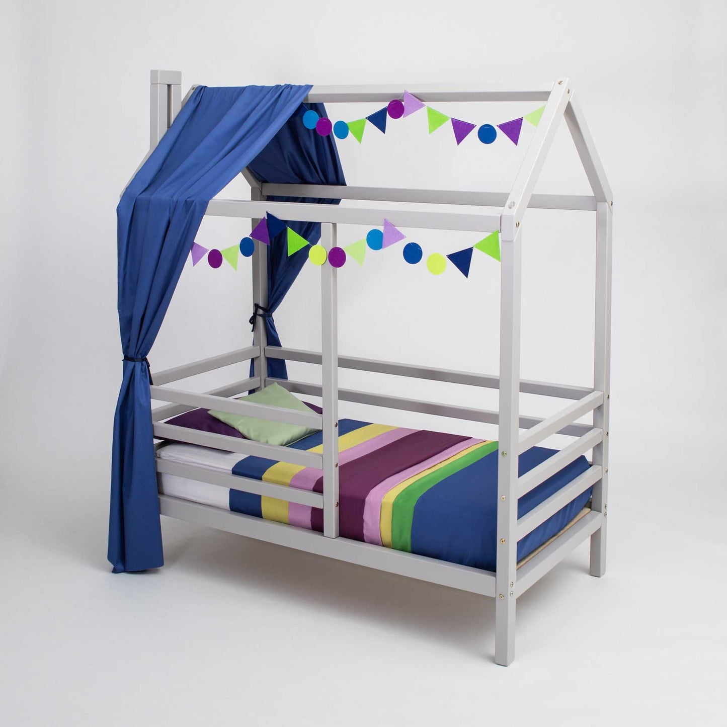 A wooden house bed on legs with a fence, with a blue canopy and striped curtains.