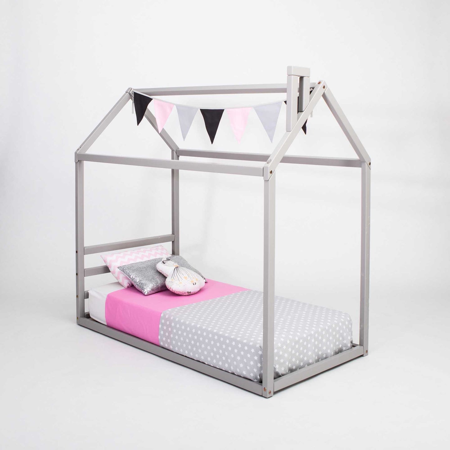 A Sweet Home From Wood children's house bed with a horizontal headboard, grey frame, and pink and grey bedding.