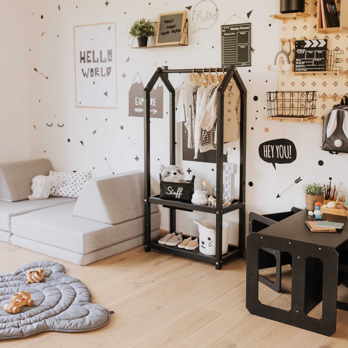 A black and white kids room with polka dots on the wall, featuring a Montessori wardrobe from Sweet Home From Wood for displaying toddler clothing.