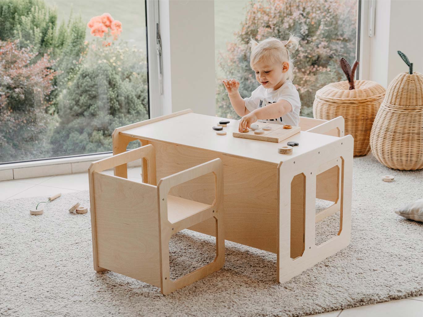 A child playing with a wooden table and chairs.