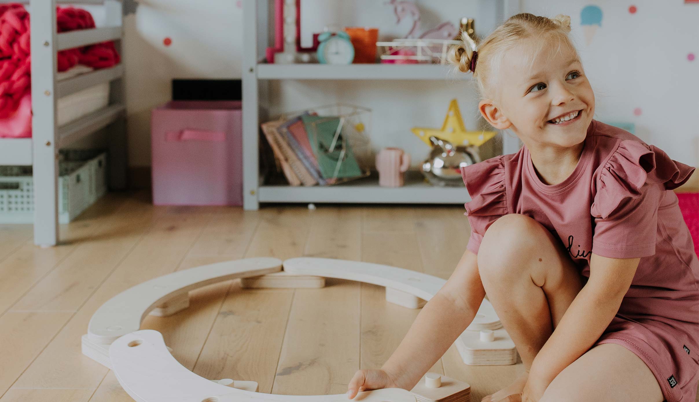 A little girl playing with a wooden toy in her room.