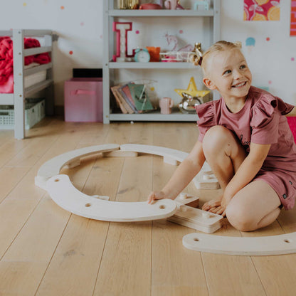 A little girl playing with Round balance beams in a room.