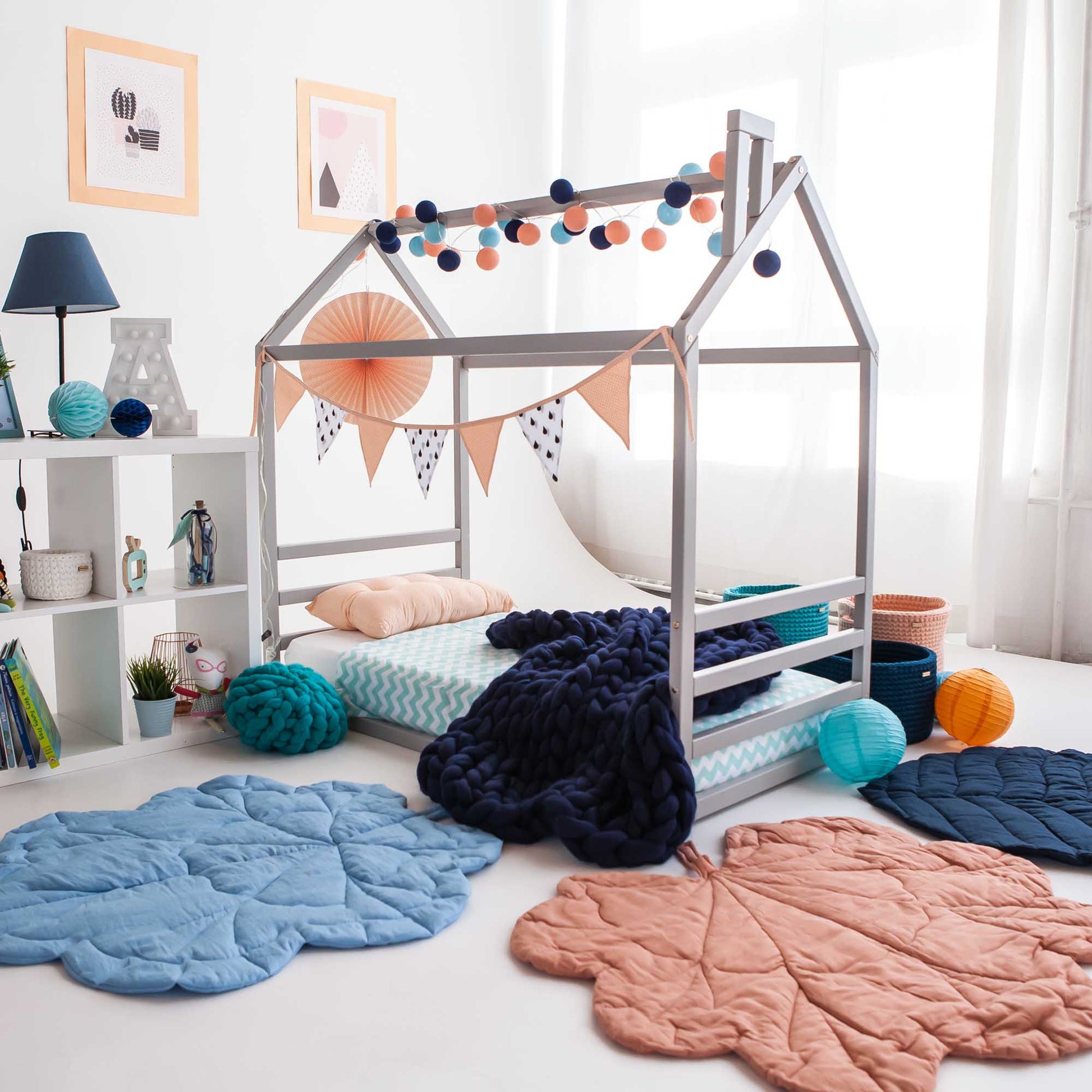 A child's room with a floor house-frame bed with a horizontal headboard and footboard and a rug.