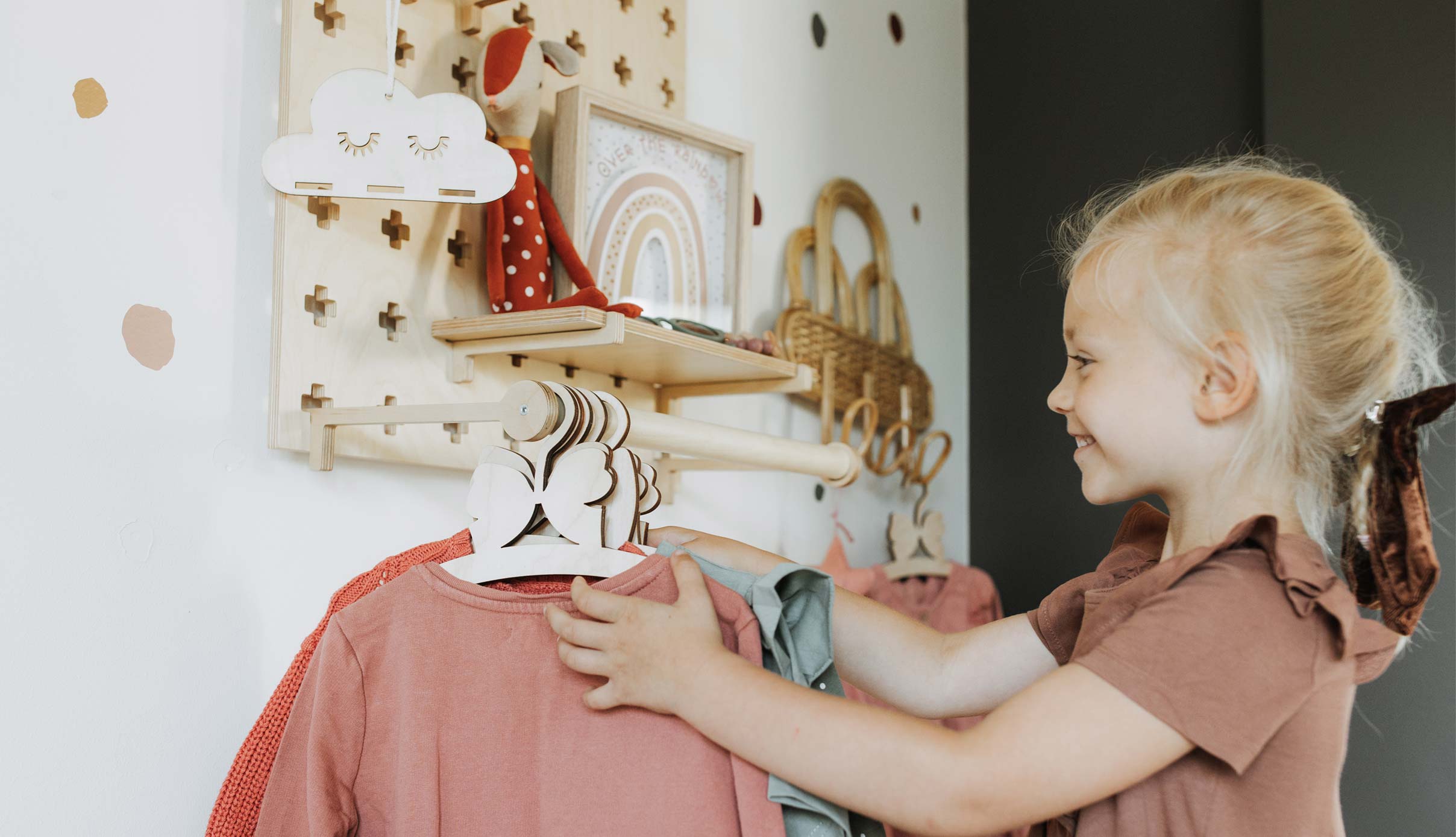 A little girl looking at clothes hanging on a rack.