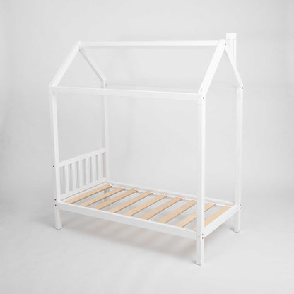 A white toddlers' house bed on legs with a headboard, raised on legs like a house bed.