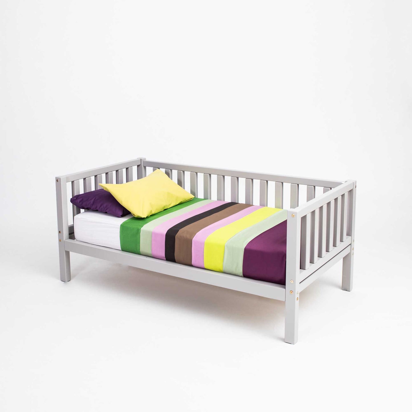 A Sweet Home From Wood Montessori-inspired children's bed with colorful striped sheets made of solid wood, specifically the Kids' platform bed on legs with 3-sided rails.