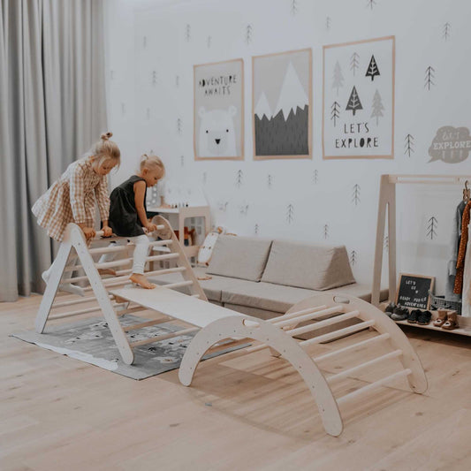 Two children playing in a room with a Sweet Home From Wood Climbing arch + Foldable climbing triangle + a ramp.