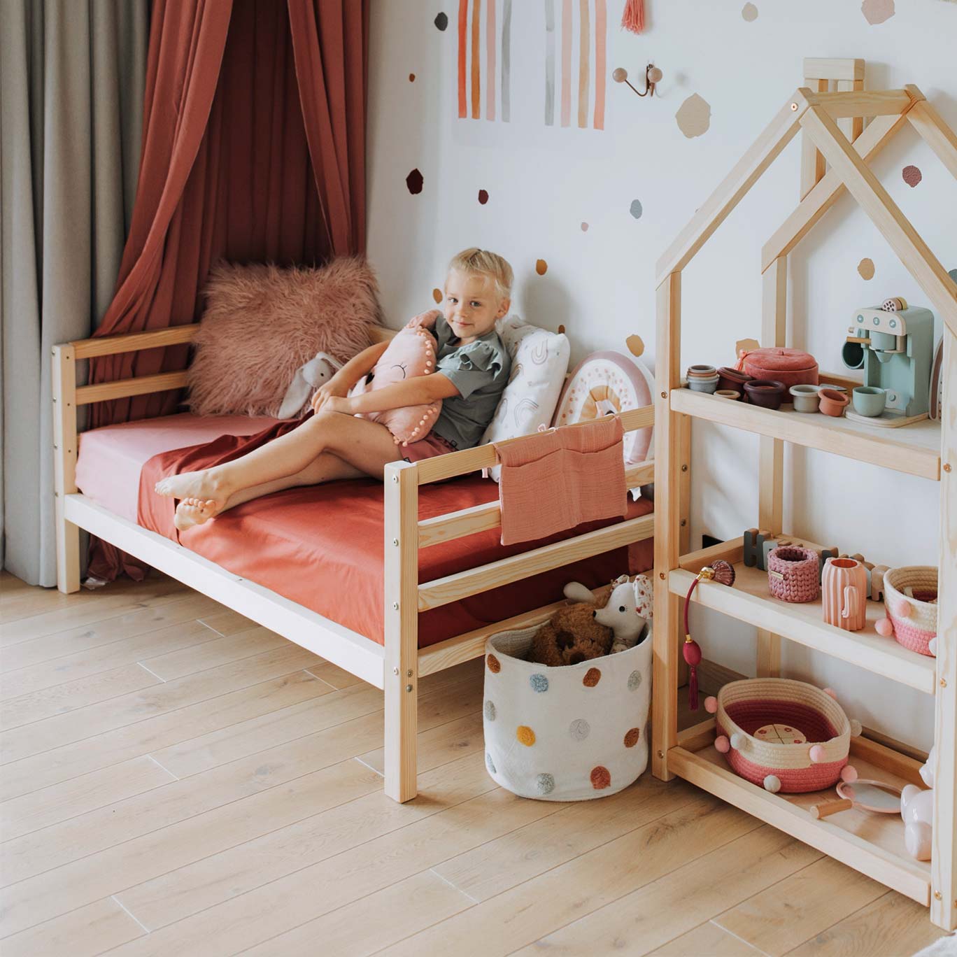 A girl is sitting on a bed in a child's room.