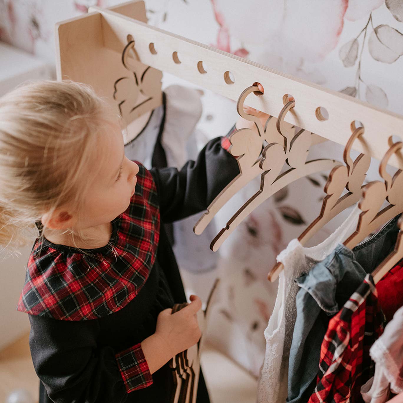 Clothing racks use cases. A girl hanging her clothes in a toddler clothing rack.