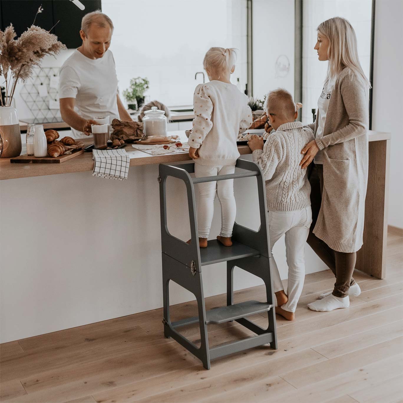 Kitchen tower usecases. A family with a girl that stands on a kitchen tower and is cooking.