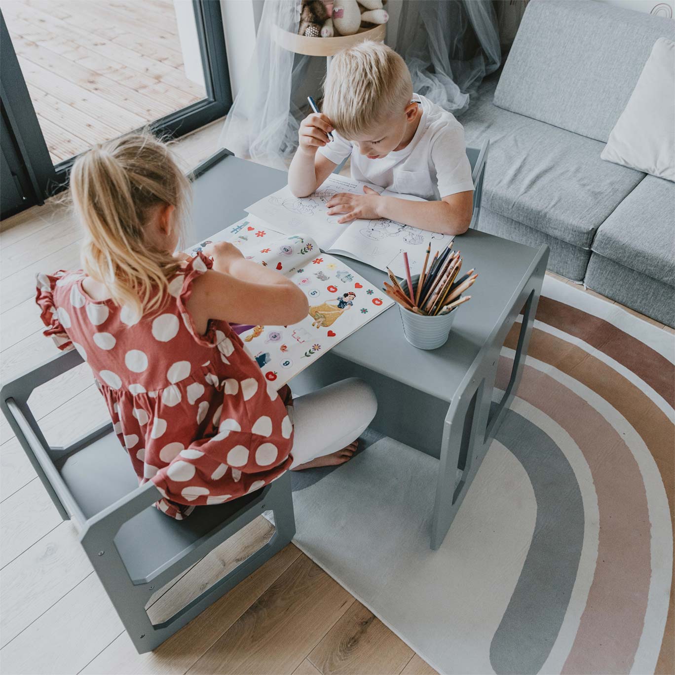 Two children sitting at a table in a living room.