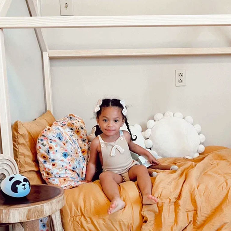 Customer photo of a girl sitting in a Montessori toddler floor house bed.