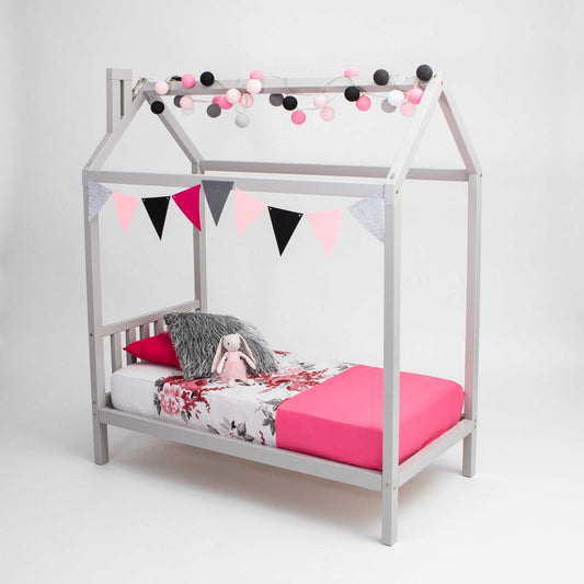 House bed on legs with a stylish headboard, adorned with a pink-grey bedding set and decorative elements, creating a cozy and aesthetically pleasing bedroom setup.