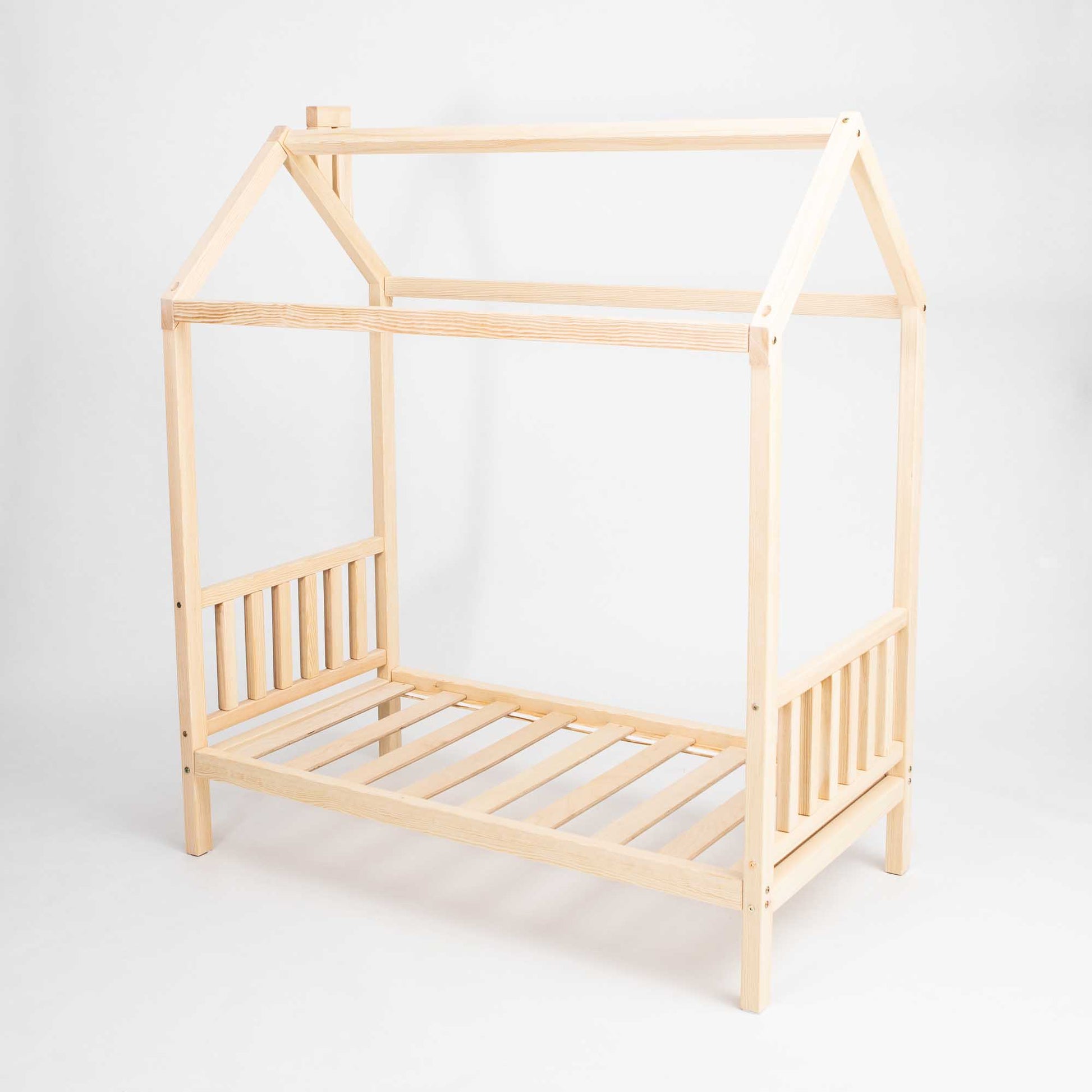 A toddler house bed on legs with a headboard and footboard with a wooden frame and slats.