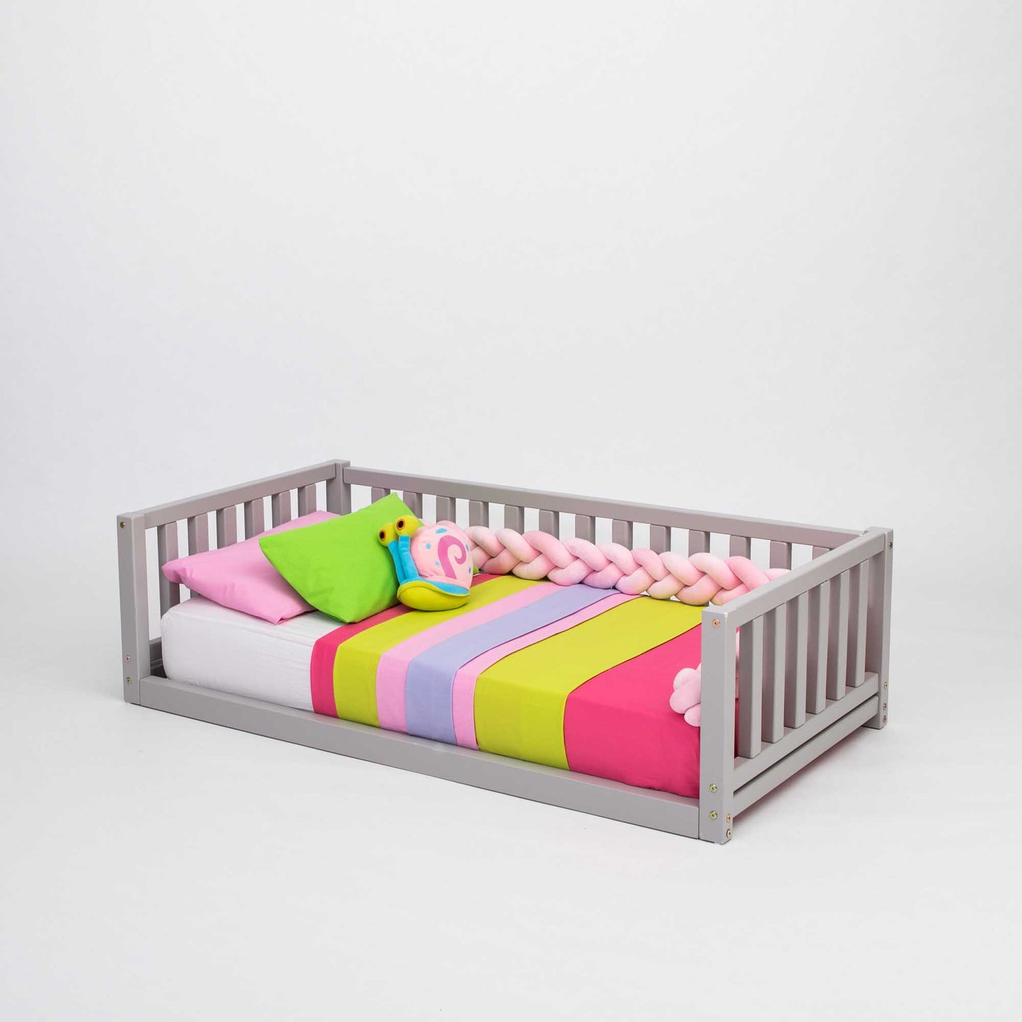 A Sweet Home From Wood 2-in-1 toddler bed on legs with a 3-sided vertical rail made of solid pine or birch wood, with a colorful blanket on the floor-level bed.