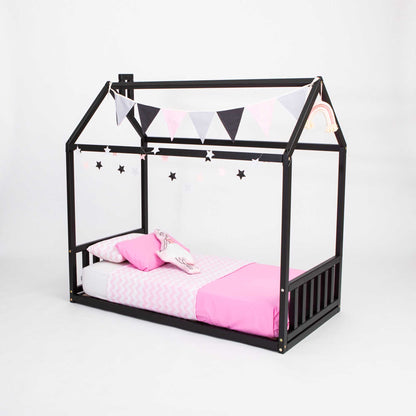 A Sweet Home From Wood toddler house bed with a headboard and footboard, featuring a sleek black frame and cozy pink bedding, creating the perfect sleep haven for a child.