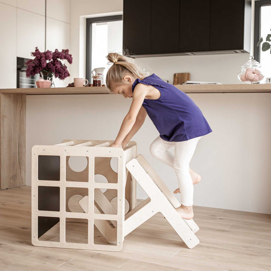 A toddler playing with a Sweet Home From Wood 2-in-1 table and chair set or activity cube on a weaning table and chair set in a kitchen.