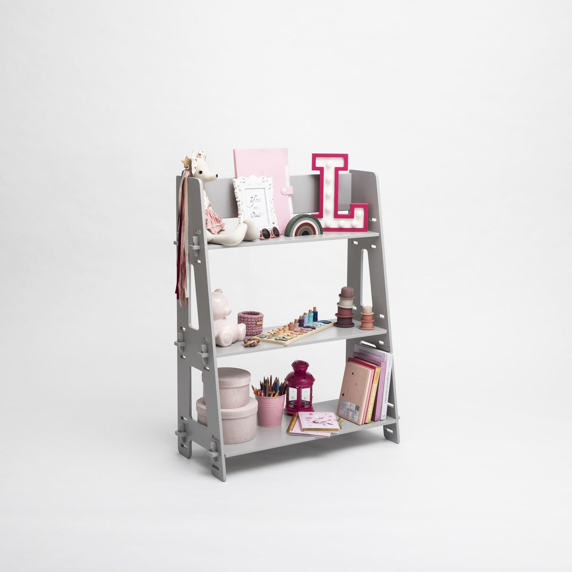 A Montessori toy shelf neatly organized with stationery, books, and decorative items against a white background.