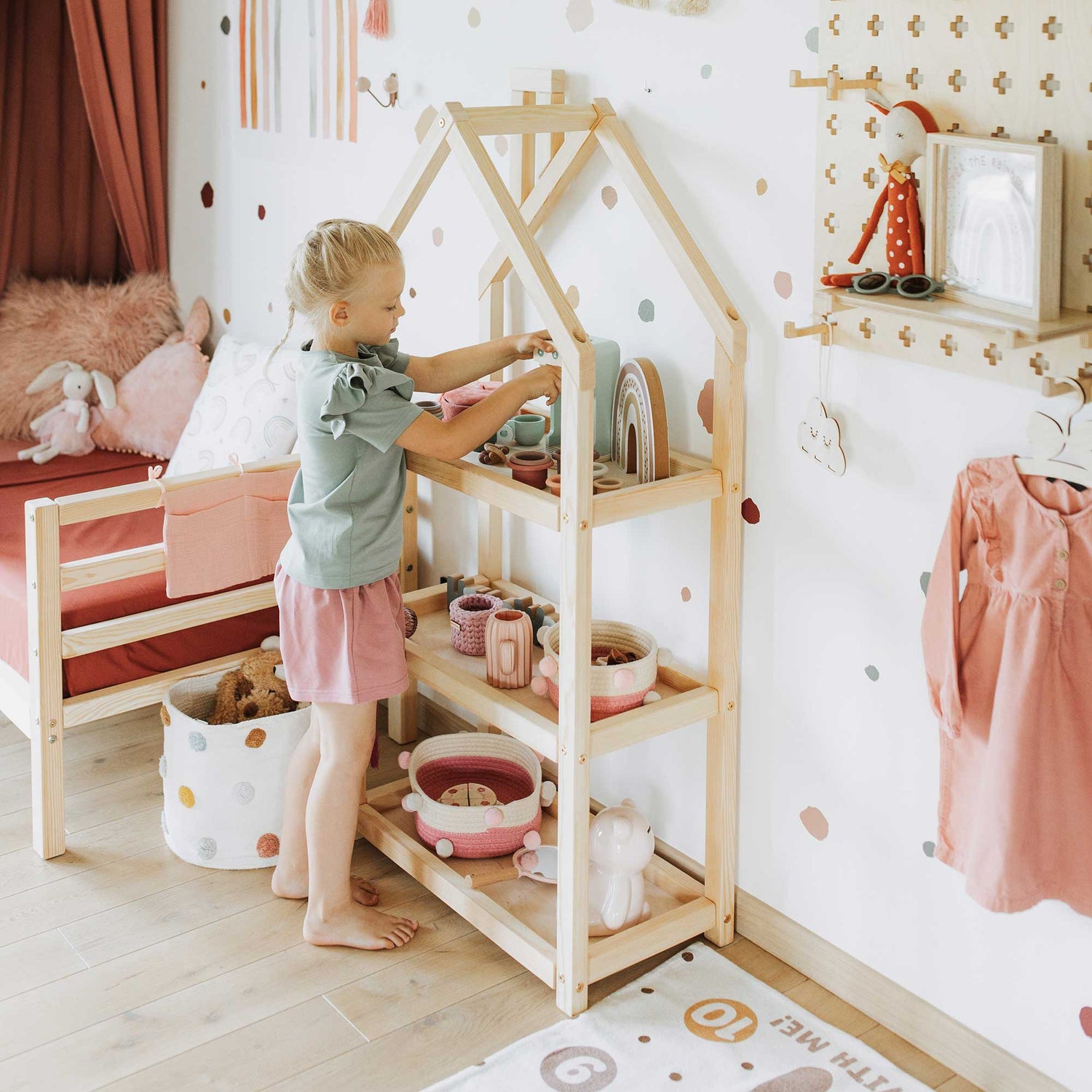 A little girl in a pink room with polka dots.