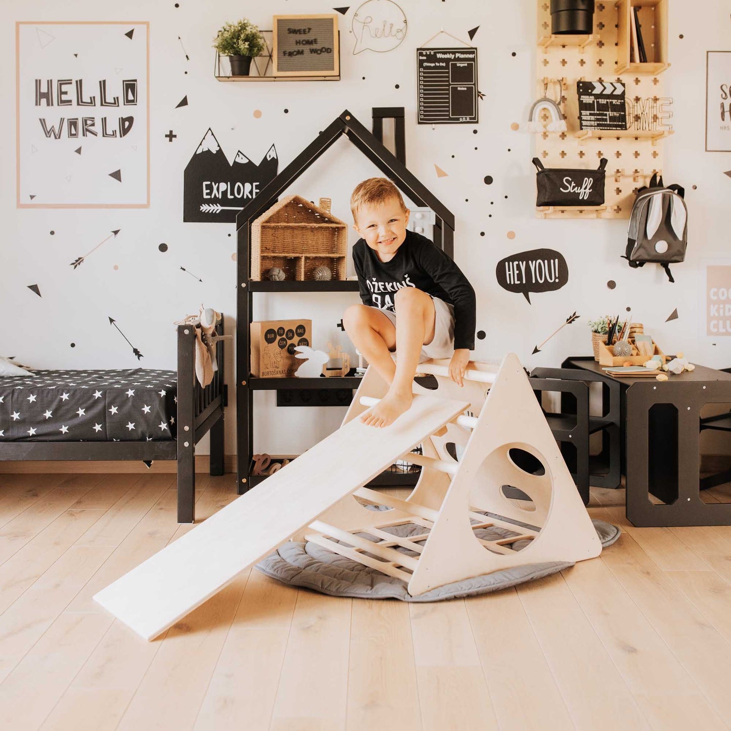A boy is playing with a Climbing triangle with sensory panels in his room.