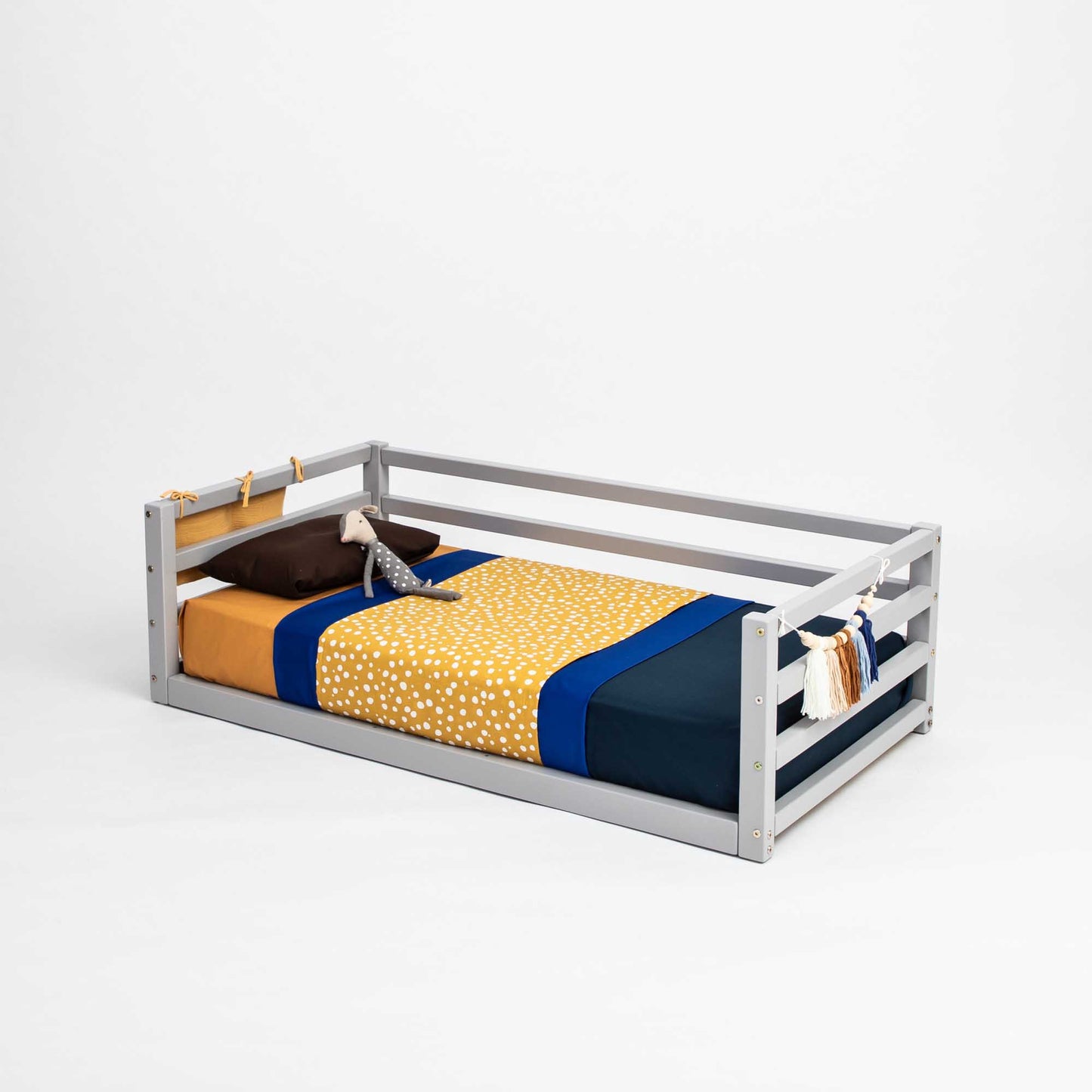A Sweet Home From Wood children's floor level bed with a transitional design, featuring a 3-sided safety rail and an adorable teddy bear.
