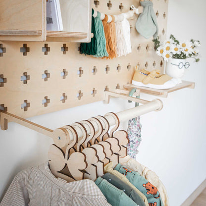 A child's room with clothes hanging on a Sweet HOME from wood Pegboard with Clothes Hanger shelves.