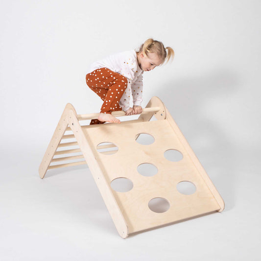 A little girl climbing on a Transformable climbing triangle + Transformable climbing gym + a ramp.