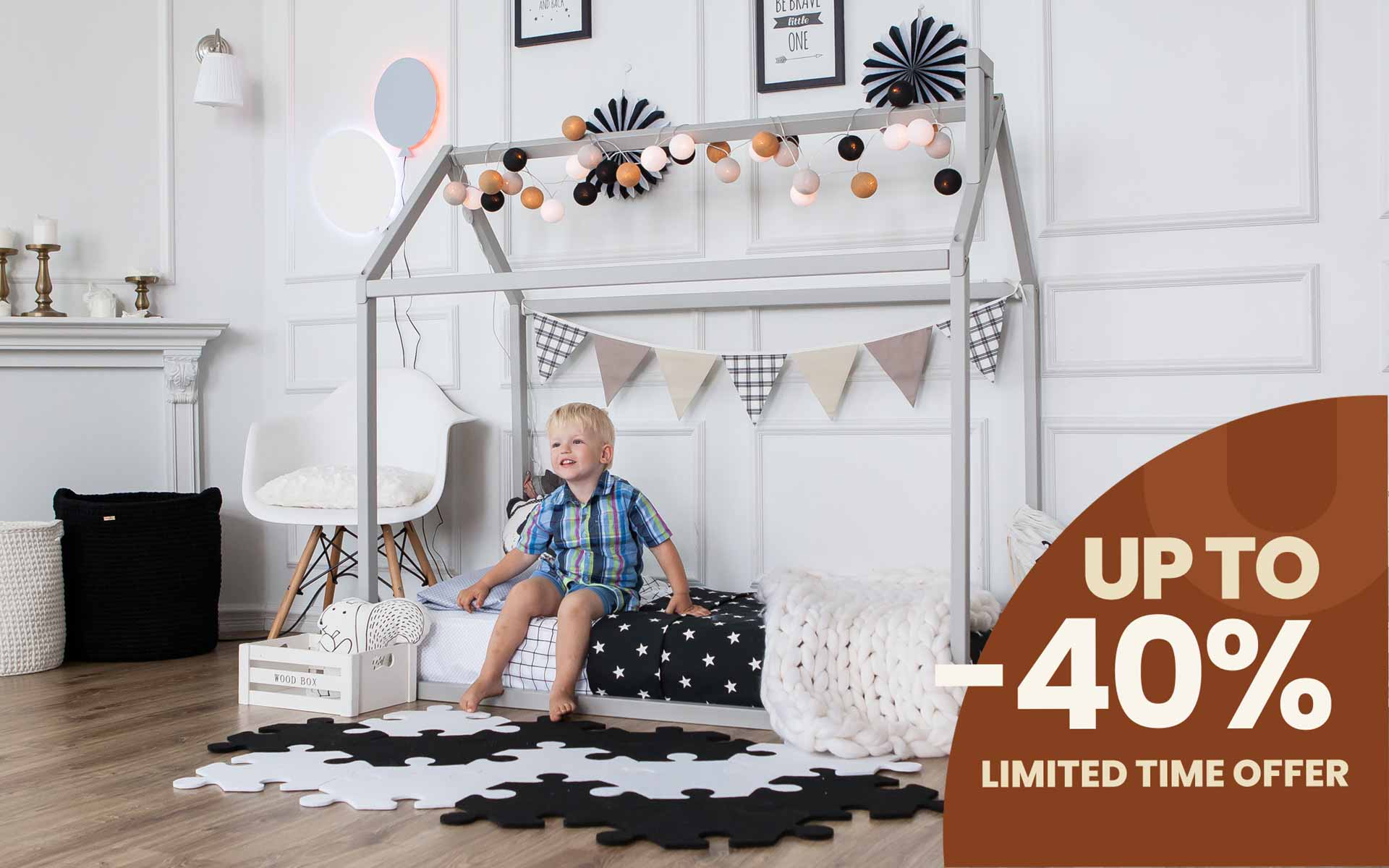 A child's room with a Montessori house bed and a boy sitting in it.