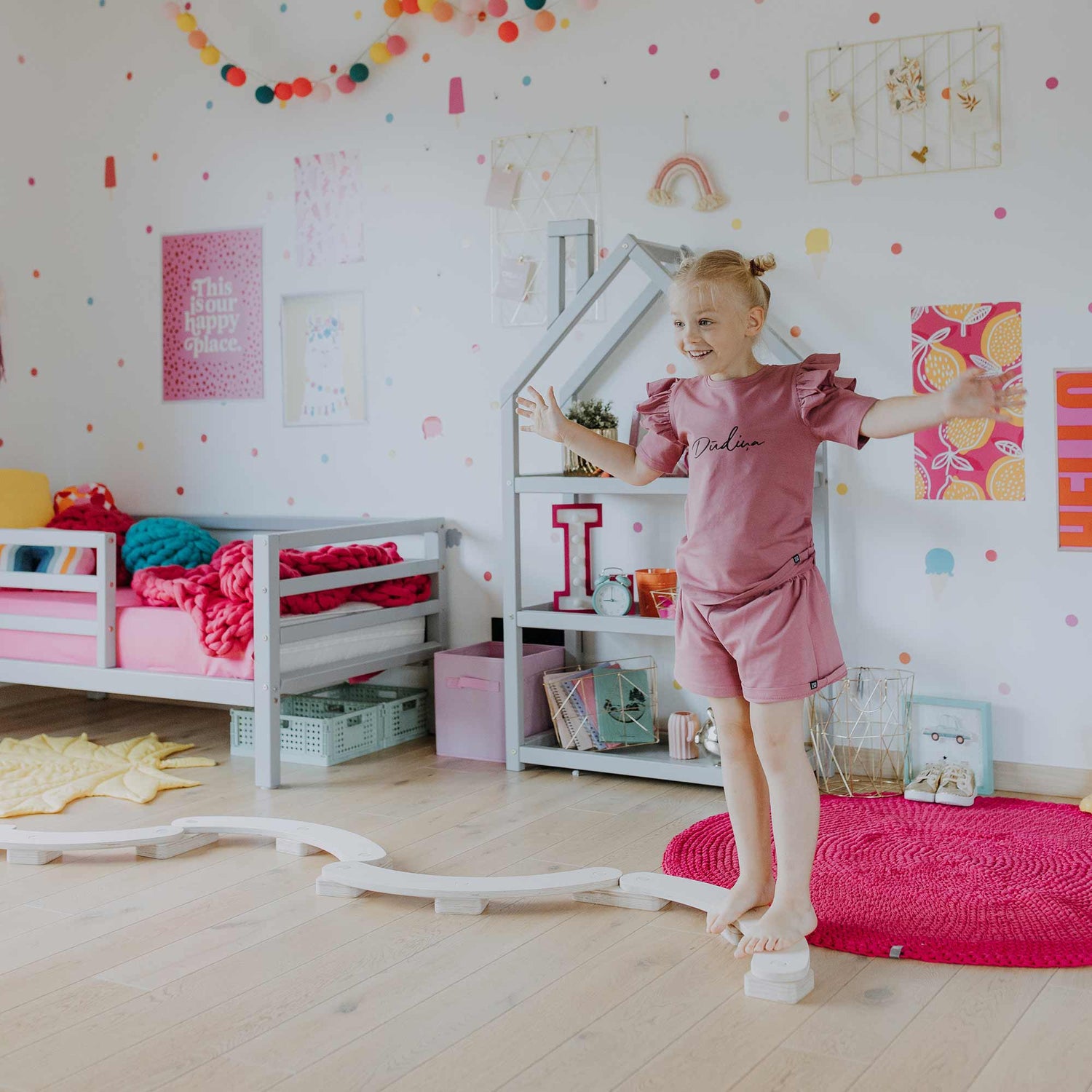 A little girl standing in a pink and white room.