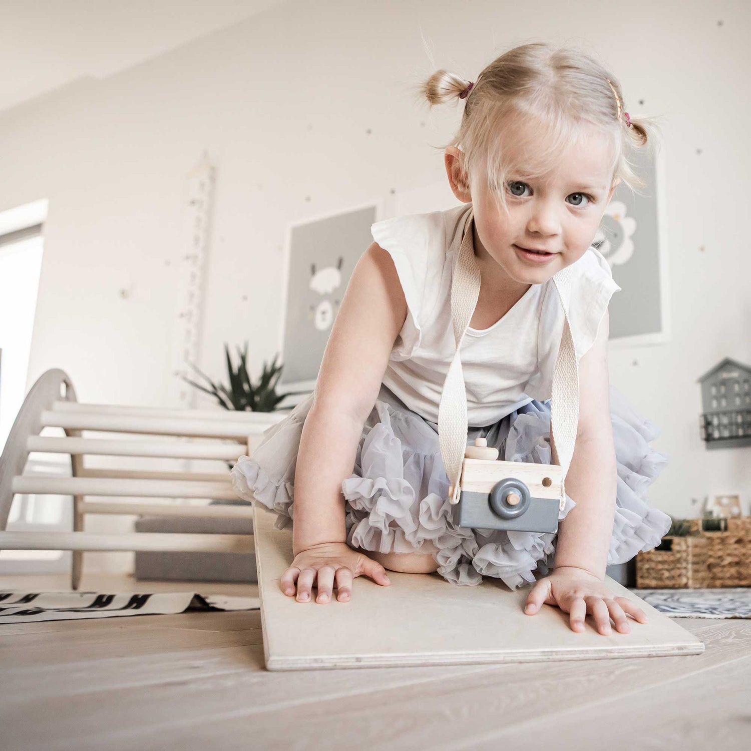 A little girl playing with a wooden toy on the floor.