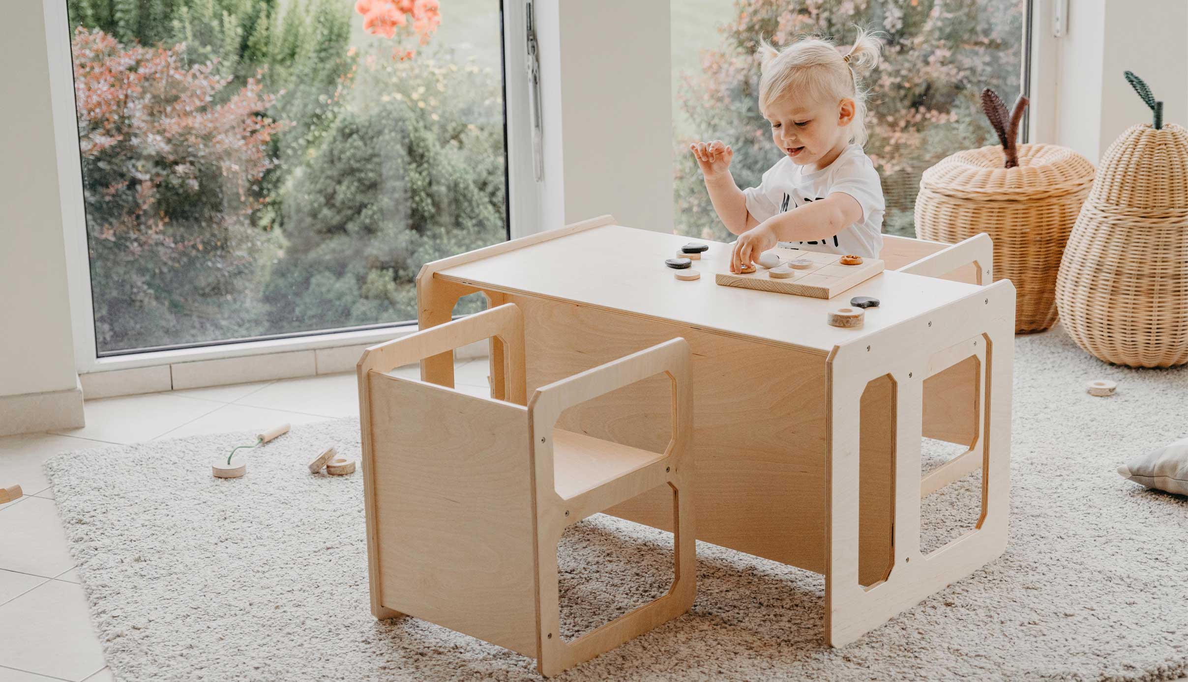 A child playing with a wooden table and chair.