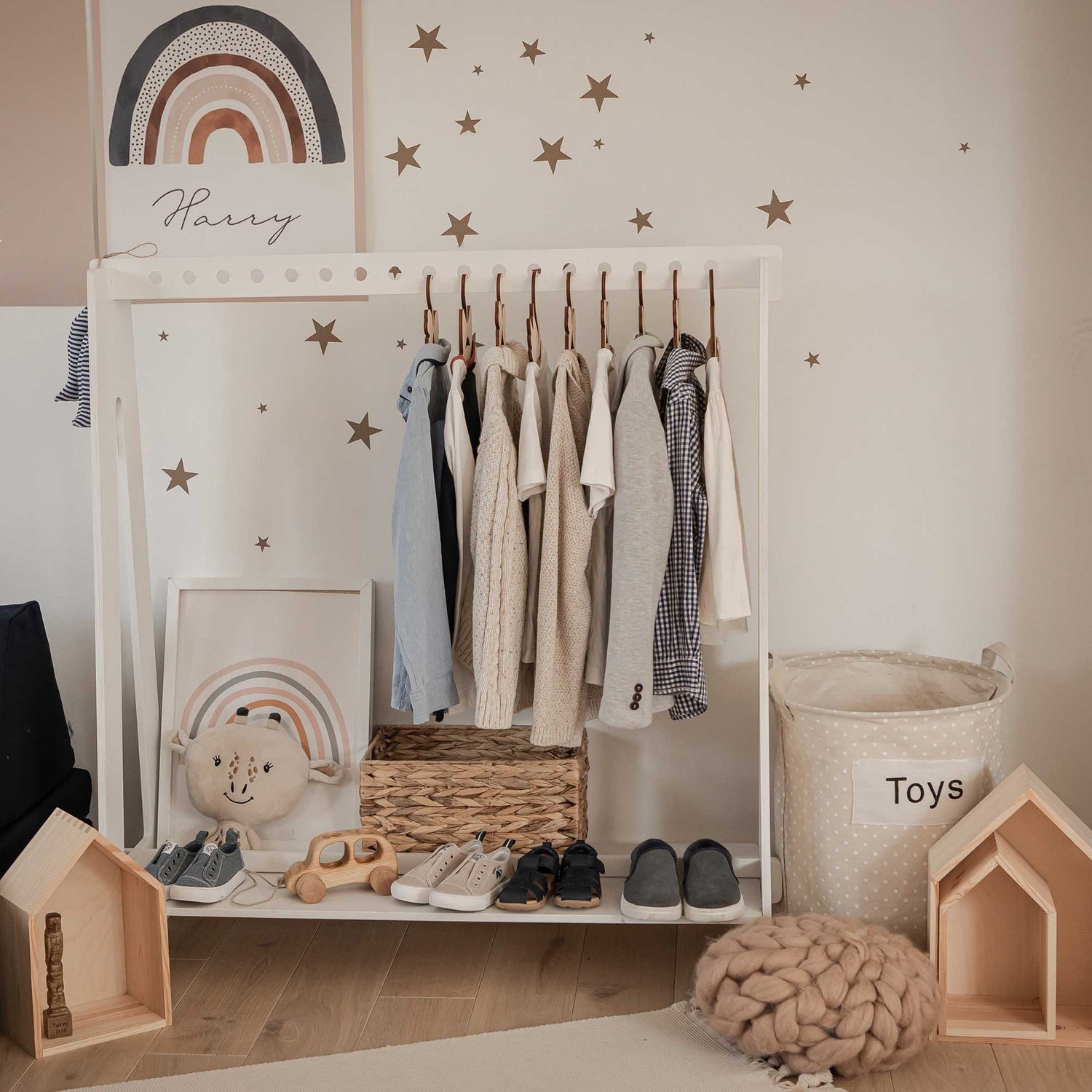 A child's room with clothes on a rack and stars on the wall.