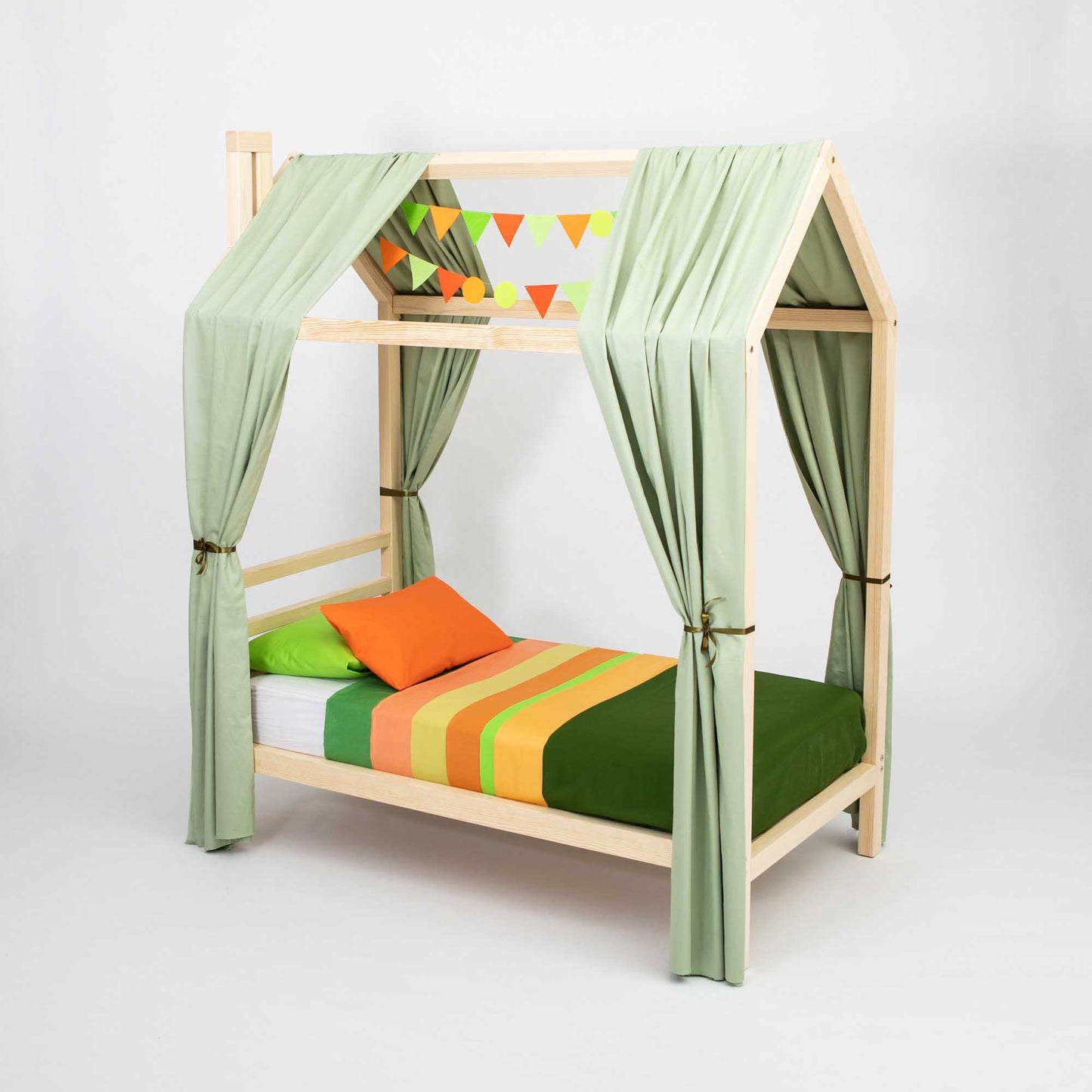 A Kids' house bed on legs with a headboard, adorned with green curtains, a mattress featuring colorful bedding in green, yellow, and orange hues, and pillows in matching green and orange colors creates a cozy toddler bed. A banner with triangle flags hangs above, adding a playful touch perfect for co-sleeping arrangements.