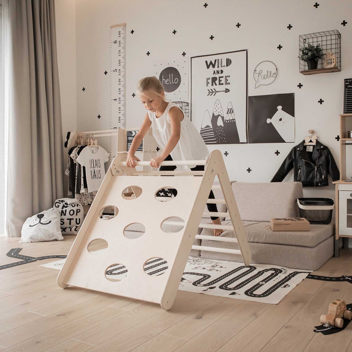 A little girl is playing with the Transformable climbing triangle + Transformable climbing gym + a ramp in her room.