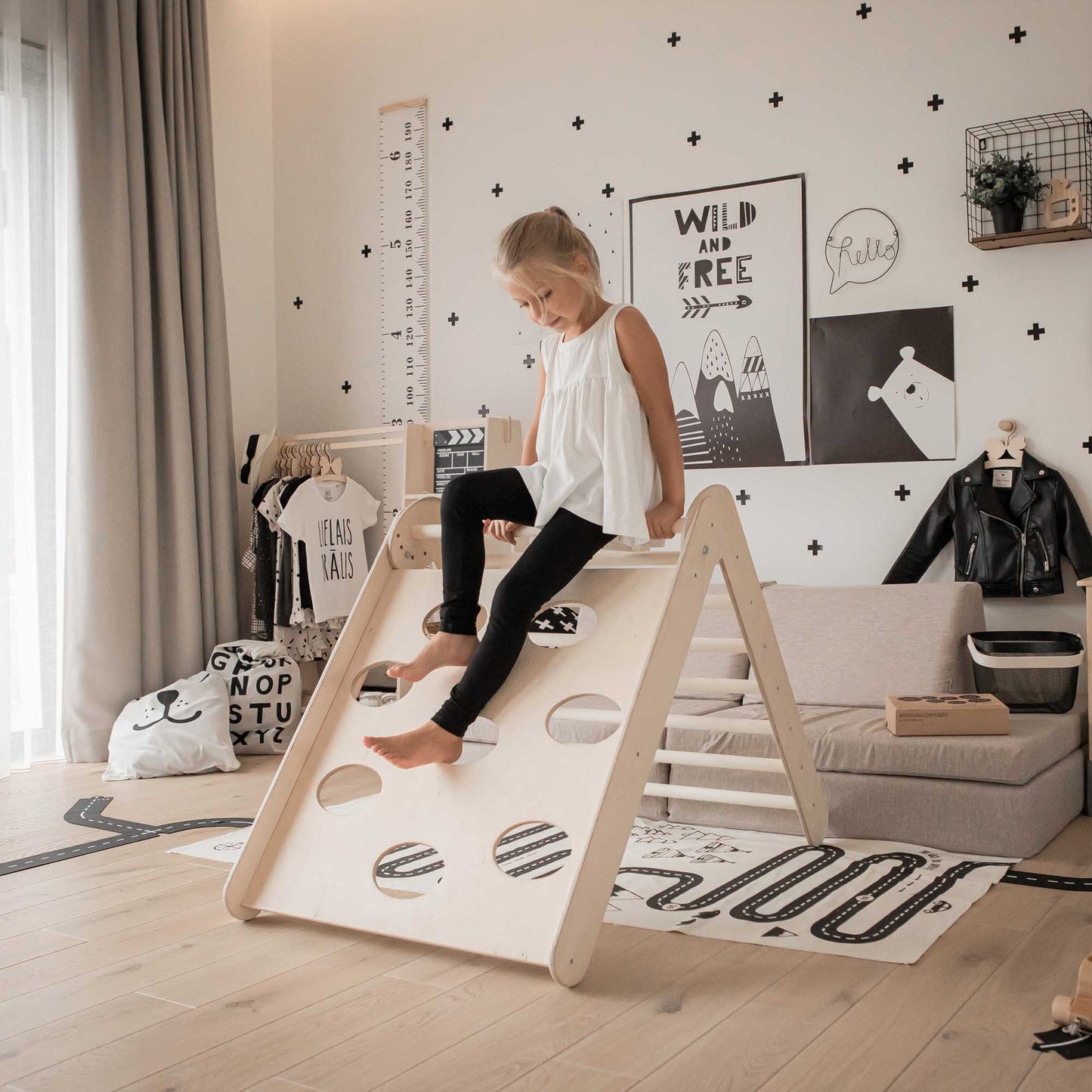 A little girl is joyfully climbing on a Transformable triangle + climbing cube / table and chair + a ramp in a room filled with climbing toys.
