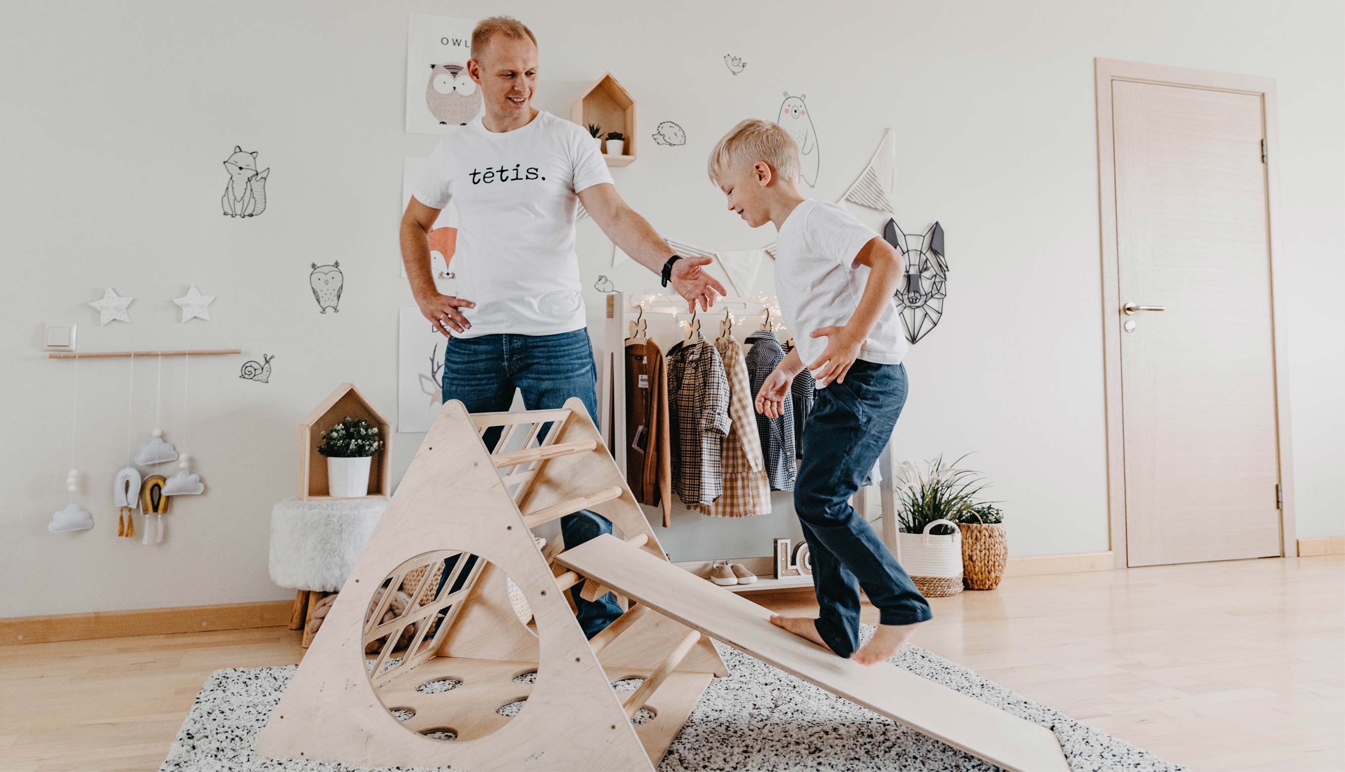 A father and son playing with a wooden slide in a room.