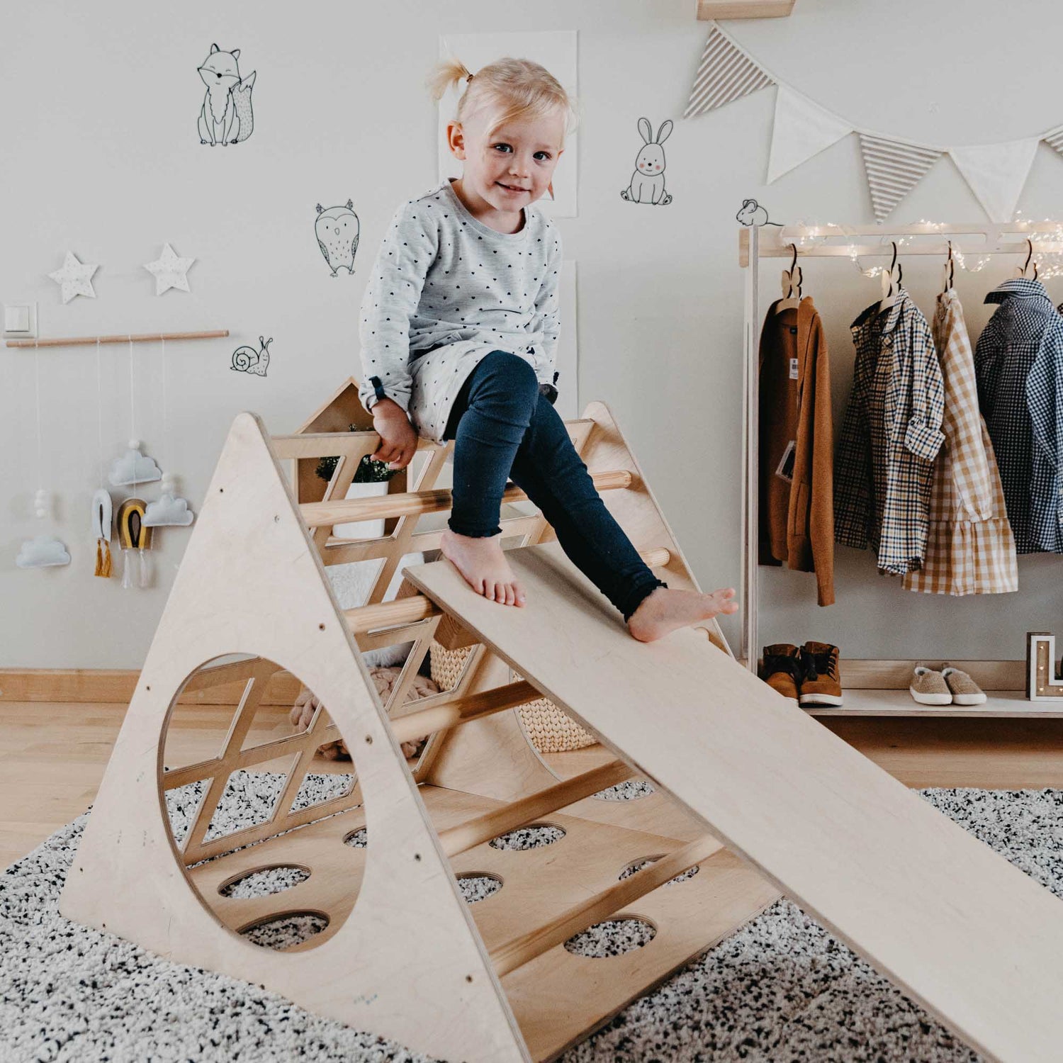 A child is sitting on a Climbing triangle with sensory panels in a room, developing their motor skills.