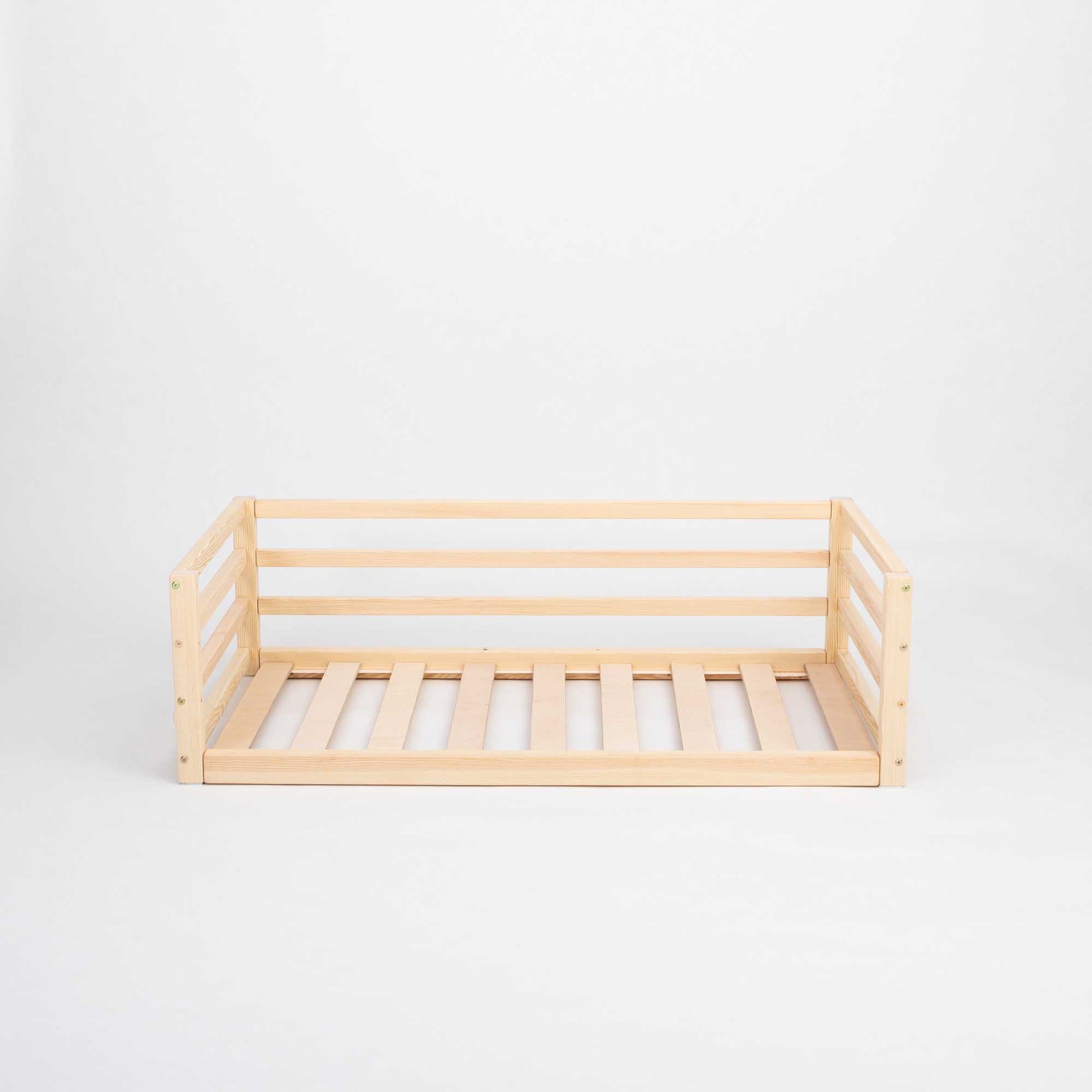 A Sweet Home From Wood transitional children's bed with wooden slats and a safety rail.