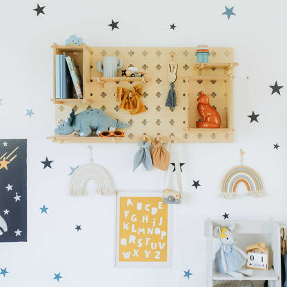 A child's room with stars on the wall and a Sweet HOME from wood Pegboard Wall Shelf for organization.
