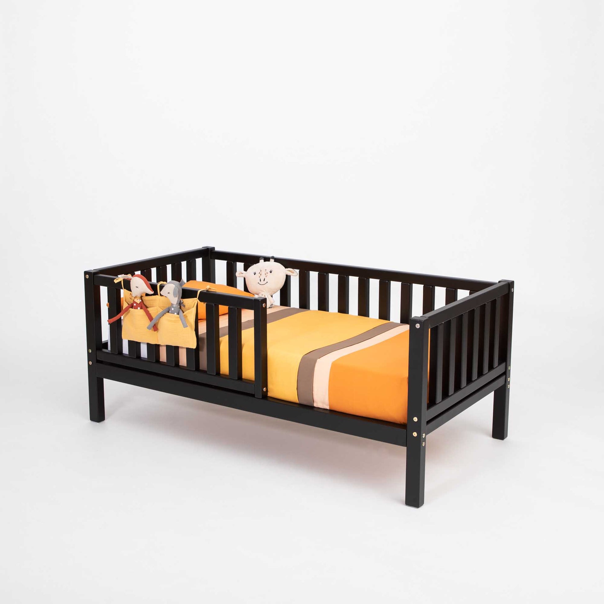 An orange and black striped 2-in-1 toddler bed on legs with a vertical rail fence and a sheet, by Sweet Home From Wood.