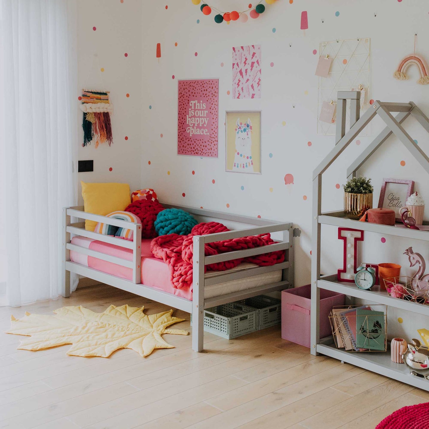 A girl's room with a Sweet Home From Wood 2-in-1 transformable kids' bed with a horizontal rail fence and a colorful rug.