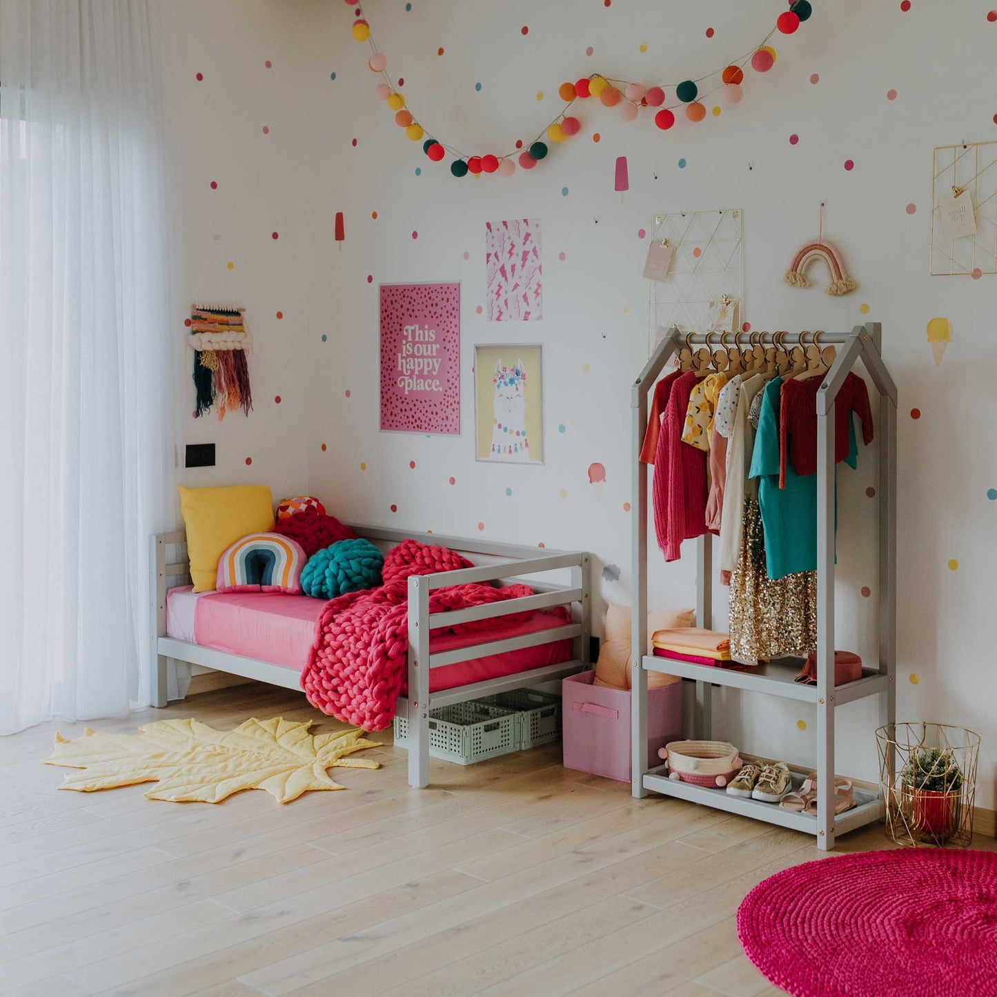 A girl's room with a colorful polka dot theme and a Sweet Home From Wood 2-in-1 transformable kids' bed with a 3-sided horizontal rail.