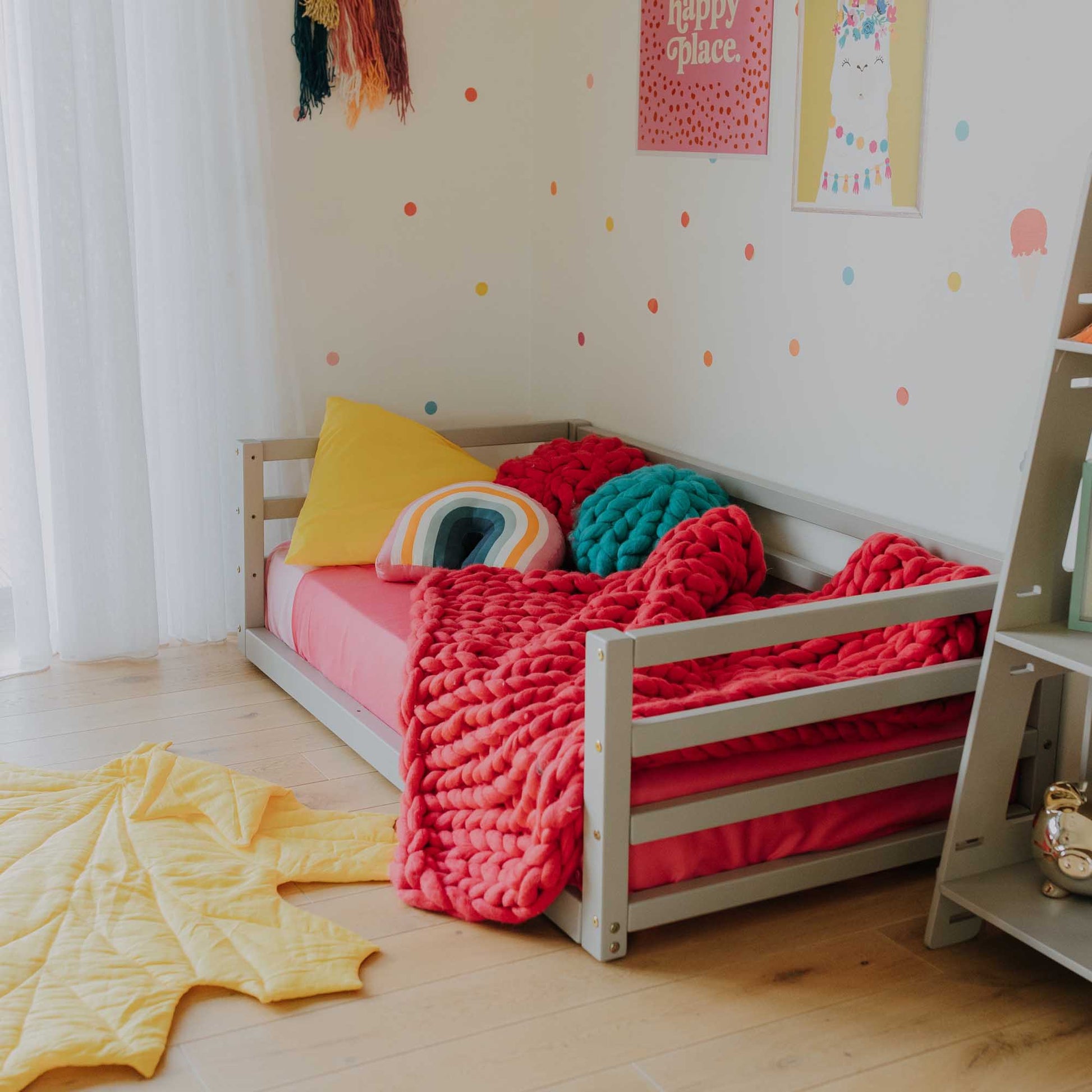 A child's room with a Sweet Home From Wood 2-in-1 transformable kids' bed with a 3-sided horizontal rail and a shelf.