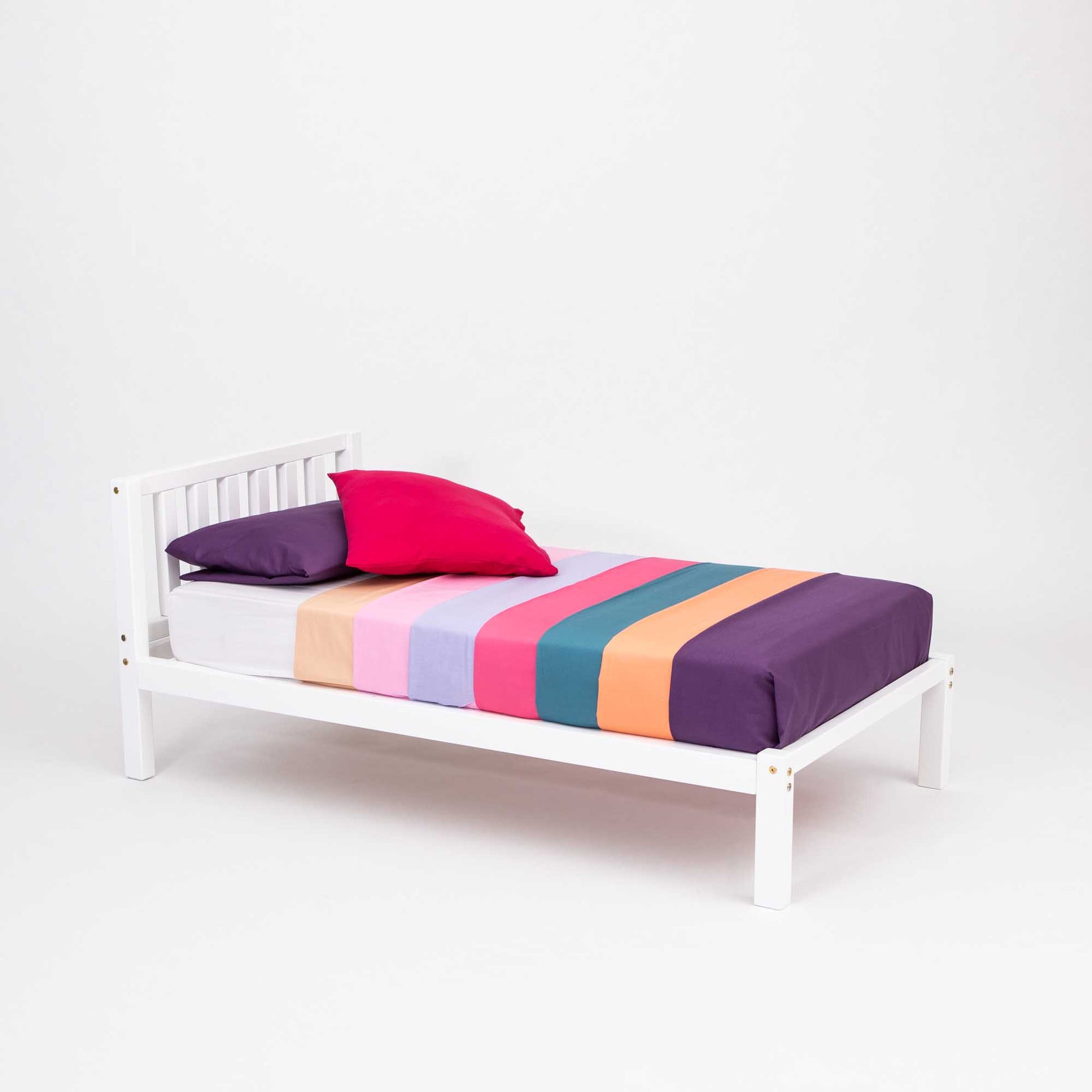 A 2-in-1 toddler bed on legs with a vertical rail headboard from Sweet Home From Wood, with colorful striped sheets.